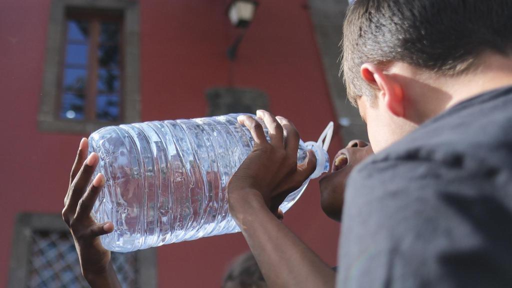 Dos estudiantes de primaria beben agua en una salida cultural.