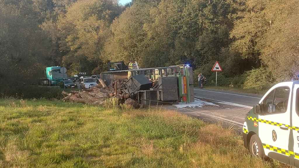 El vehículo volcado con el cargamento de maderas en el suelo.