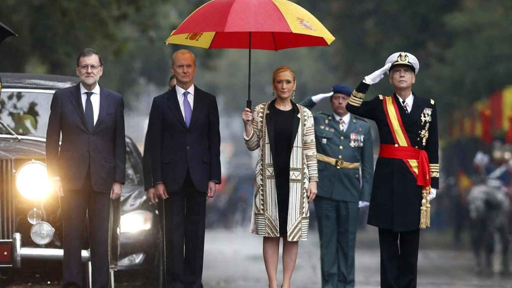 Cristina Cifuentes con su paraguas rojigualdo, junto al presidente Mariano Rajoy.