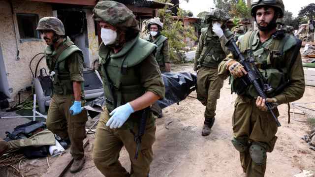 Soldados israelíes llevan un cadáver mientras recogen cuerpos tras los ataques de Gaza en el kibutz Kfar Aza.