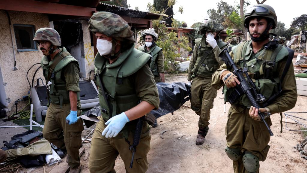 Soldados israelíes llevan un cadáver mientras recogen cuerpos tras los ataques de Gaza en el kibutz Kfar Aza.