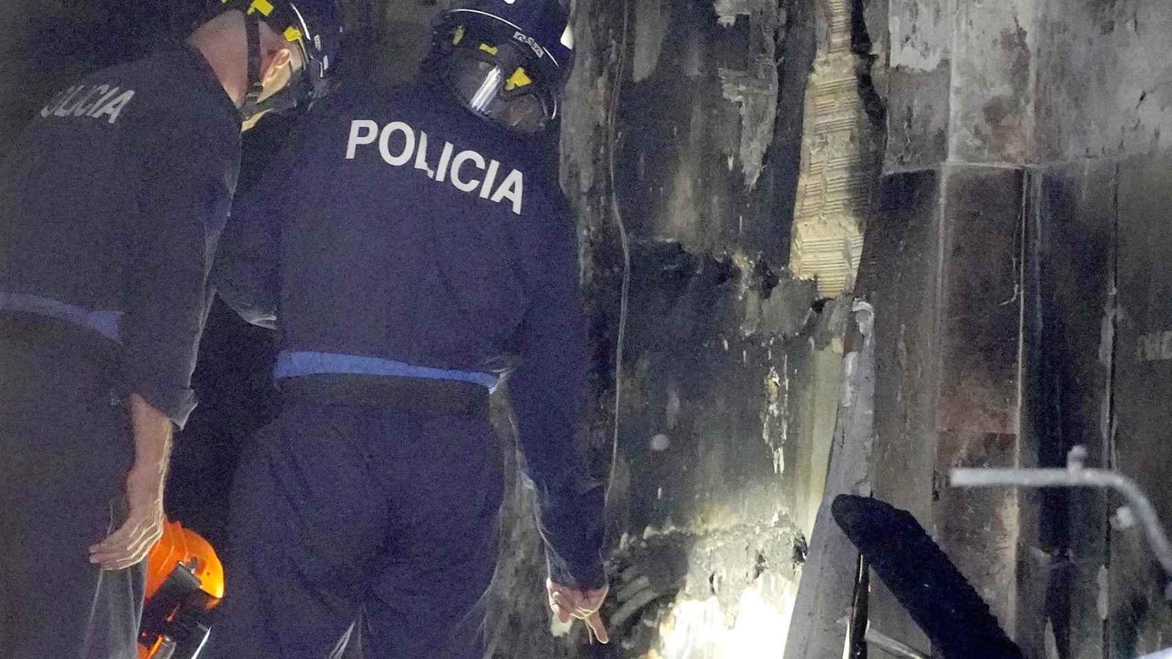 Dos agentes de policía trabajan en el edificio donde se ha producido el incendio en la calle Alfonso X el Sabio de Vigo.