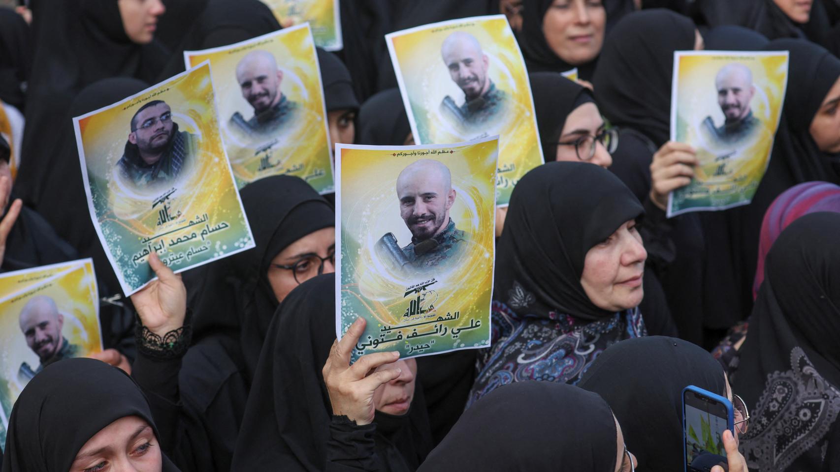 Un grupo de mujeres muestran fotografías de Ali Ftouni y Hussam Ibrahim, miembros de Hezbollah, muertos en el bombardeo israelí en el sur del Líbano.