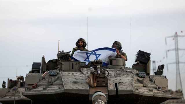 Soldados israelíes sostienen una bandera de Israel, cerca de la frontera con la Franja de Gaza.