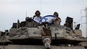 Soldados israelíes sostienen una bandera de Israel, cerca de la frontera con la Franja de Gaza.