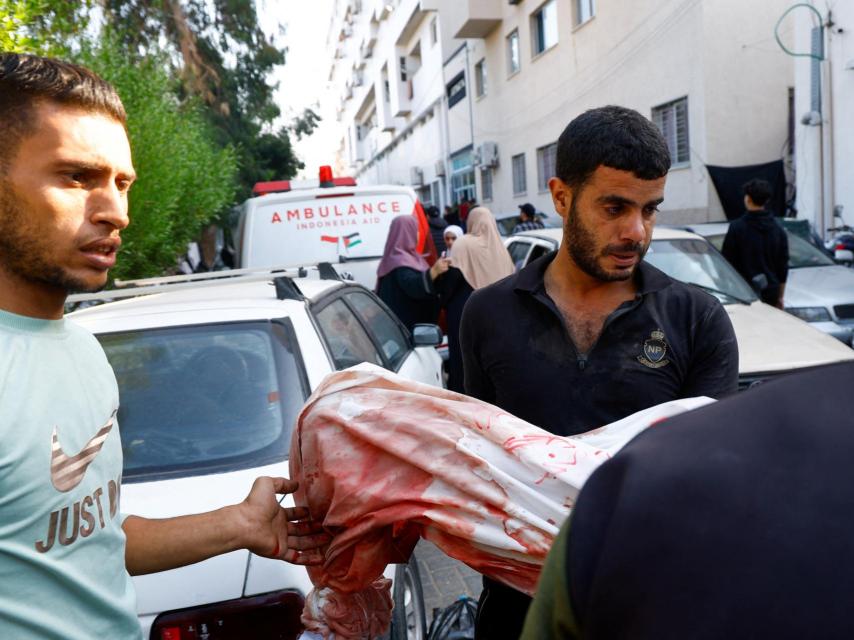 Un hombre sostiene el cuerpo de un niño víctima de los bombardeos israelíes en la ciudad de Gaza .