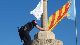 Un policía local retira una bandera con versículos del Corán de las Torres de Serrano. EE