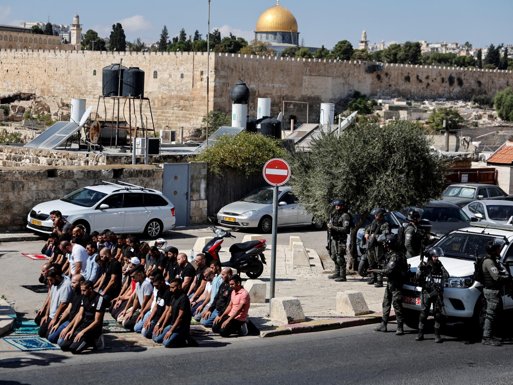 Un grupo de palestinos reza junto a miembros de la Policía de la frontera israelí en la ciudad vieja de Jerusalén.