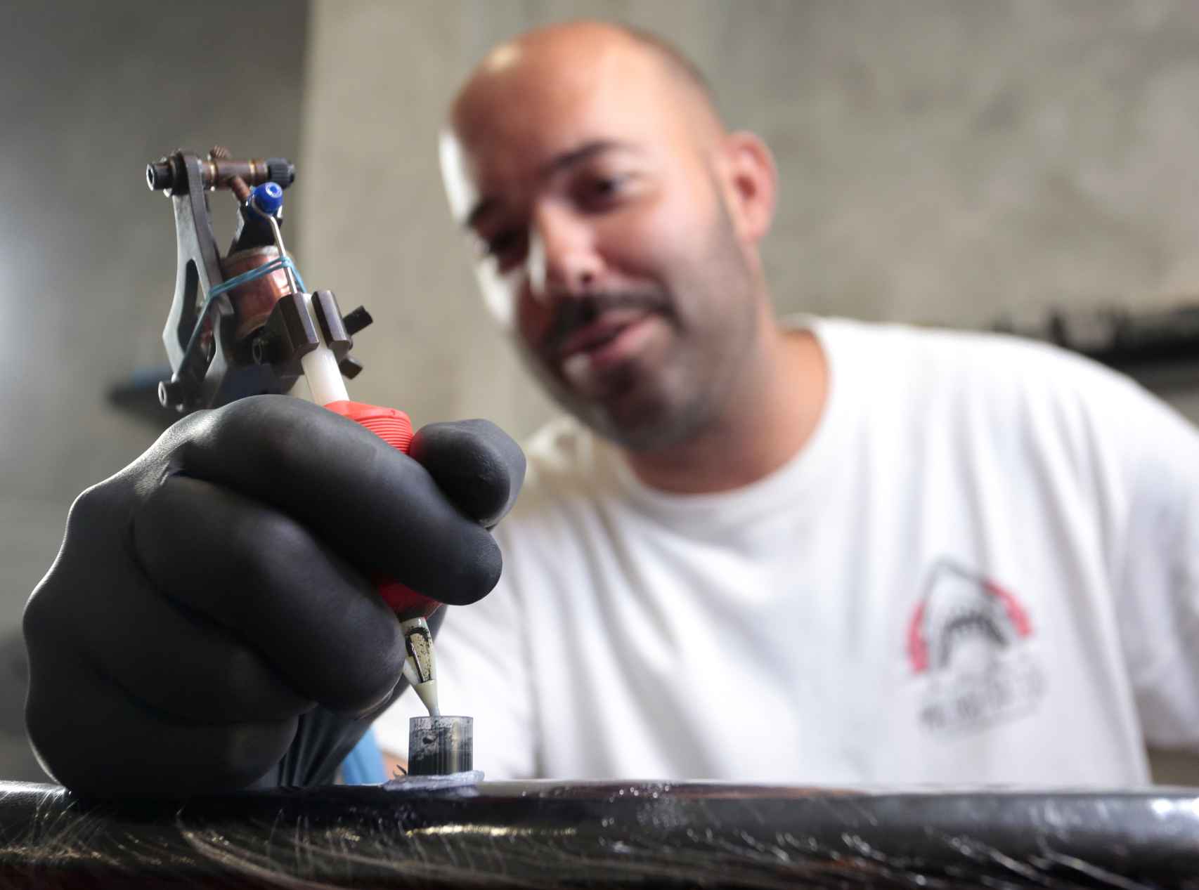 El tatuador leonés del All Street Barber & Tattoo Studio, Víctor Colado, durante la realización de un tatuaje de temática leonesa