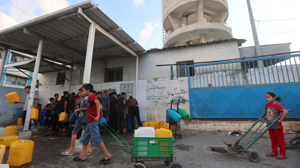 Niños palestinos recogen agua, en medio del actual conflicto palestino-israelí en Khan Younis, en el sur de la Franja de Gaza.