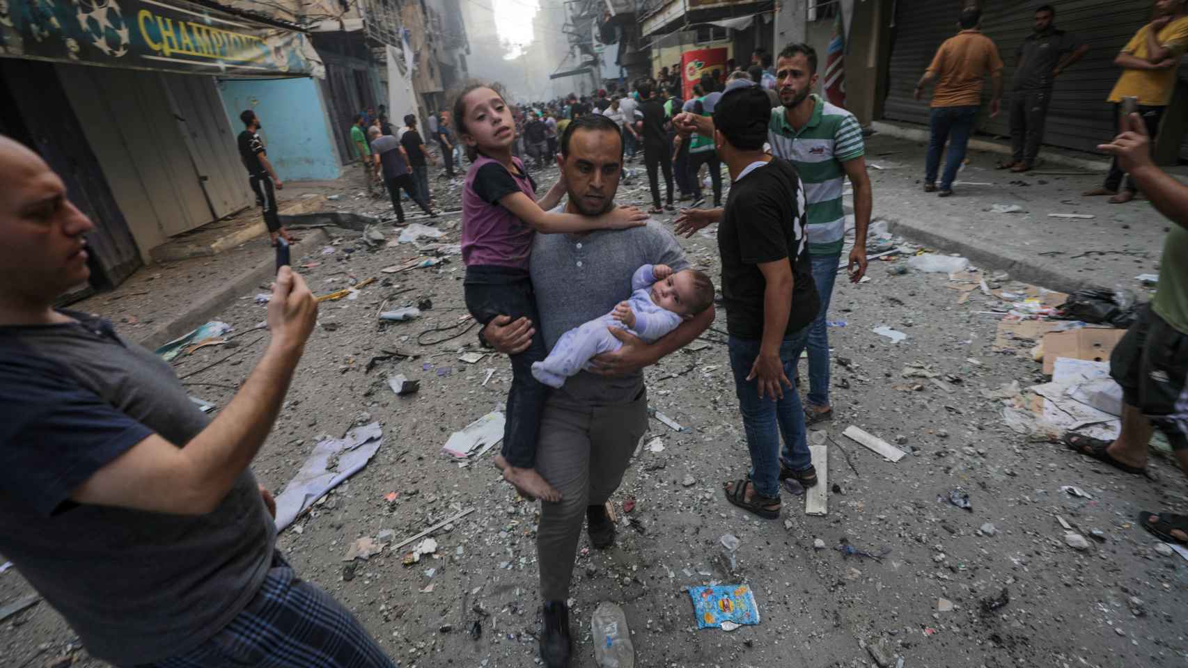 Un hombre corre con una niña tras un bombardeo israelí en un campo de refugiados cerca de la ciudad de Gaza