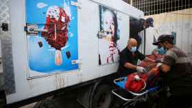 La gente traslada el cuerpo de un palestino, que murió en ataques israelíes, desde un camión de helados donde estaba guardado, mientras las morgues de los hospitales están abarrotadas.