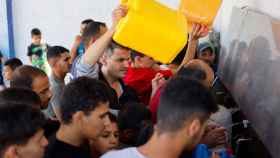 Un grupo de palestinos pelea en las colas para recoger agua potable.