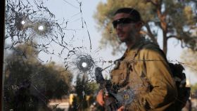 Un soldado israelí observa los agujeros de bala de un cristal tras la masacre de Hamás en el kibutz de Beeri.