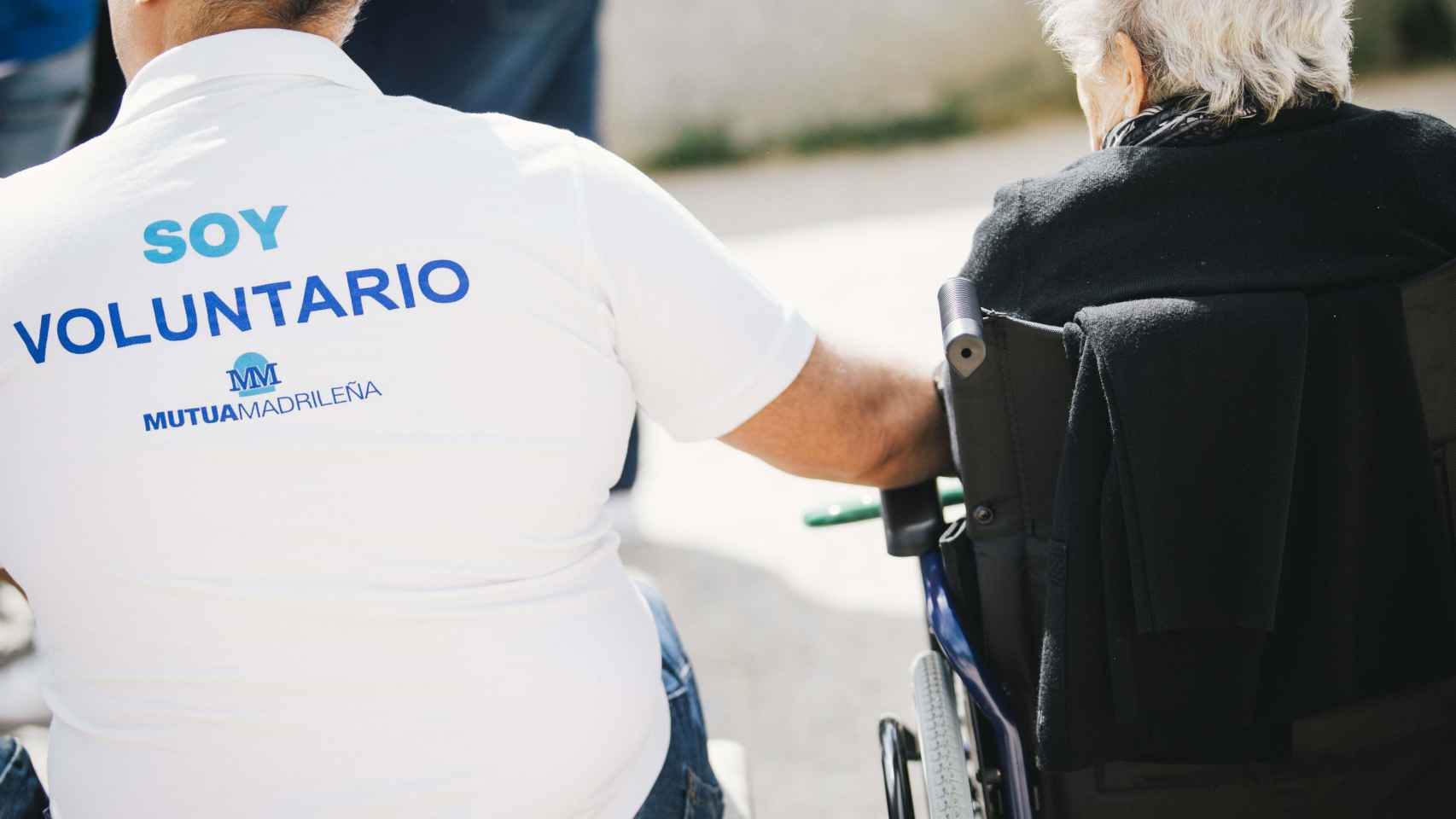 Un voluntario de Mutua Madrileña ayuda a una persona mayor con movilidad reducida.