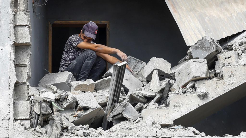 Un hombre sentado entre los escombros tras un ataque israelí a una casa en Gaza.