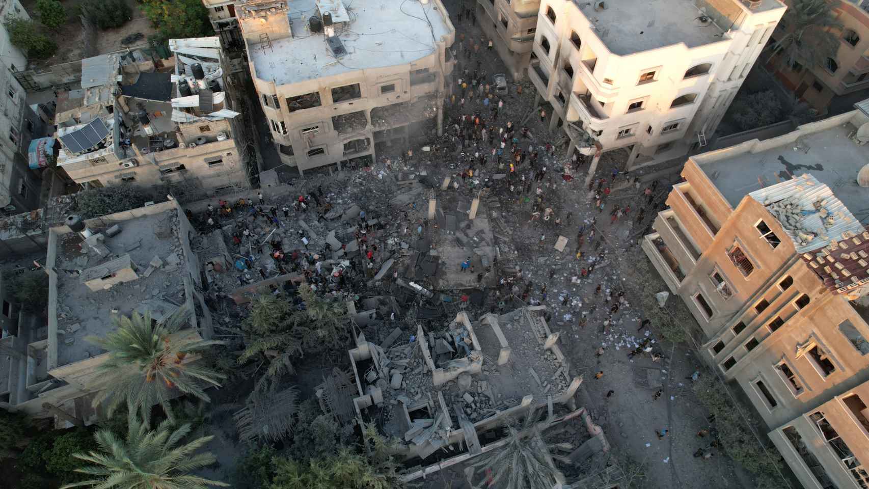 Varias personas se reúnen en las ruinas de un edificio derrumbado en la ciudad de Gaza.