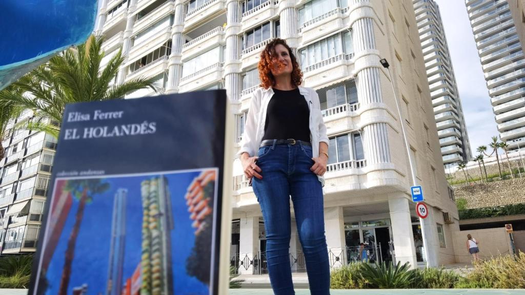 Elisa Ferrer con su novela y ante el solar en el que se construyeron las dos torres de Benidorm.