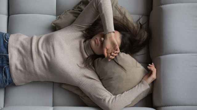 Imagen de una mujer tirada en el sofá agotada.