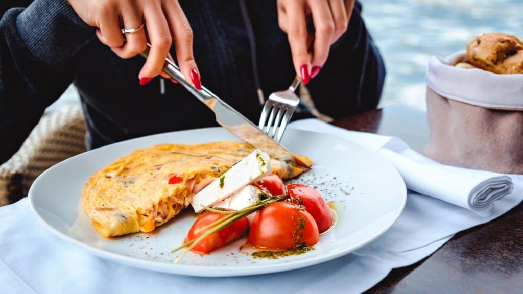 Imagen de un plato con una tortilla, ensalada de tomate y queso fresco.