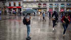 Viandantes con paraguas por Madrid.