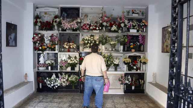 Un hombre riega las flores colocadas en la tumba de un ser querido.