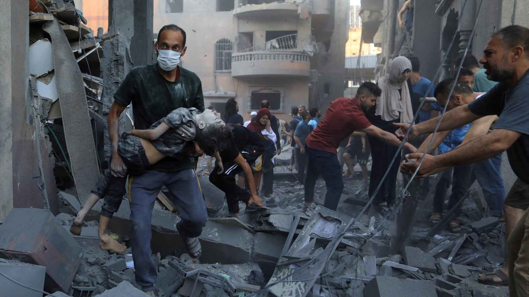 Un hombre traslada a un niño herido tras un bombardeo de Israel sobre la localidad de Jan Yunis.
