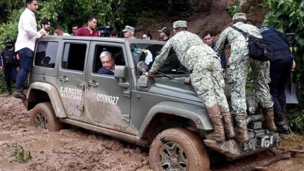 Varios militares del ejército mexicano intentan sacar al coche del barro.