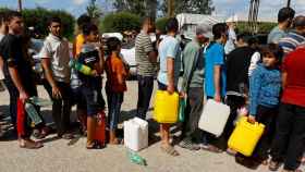 Varios hombres y niños hacen cola para conseguir gasolina en la ciudad de Jan Yunis.