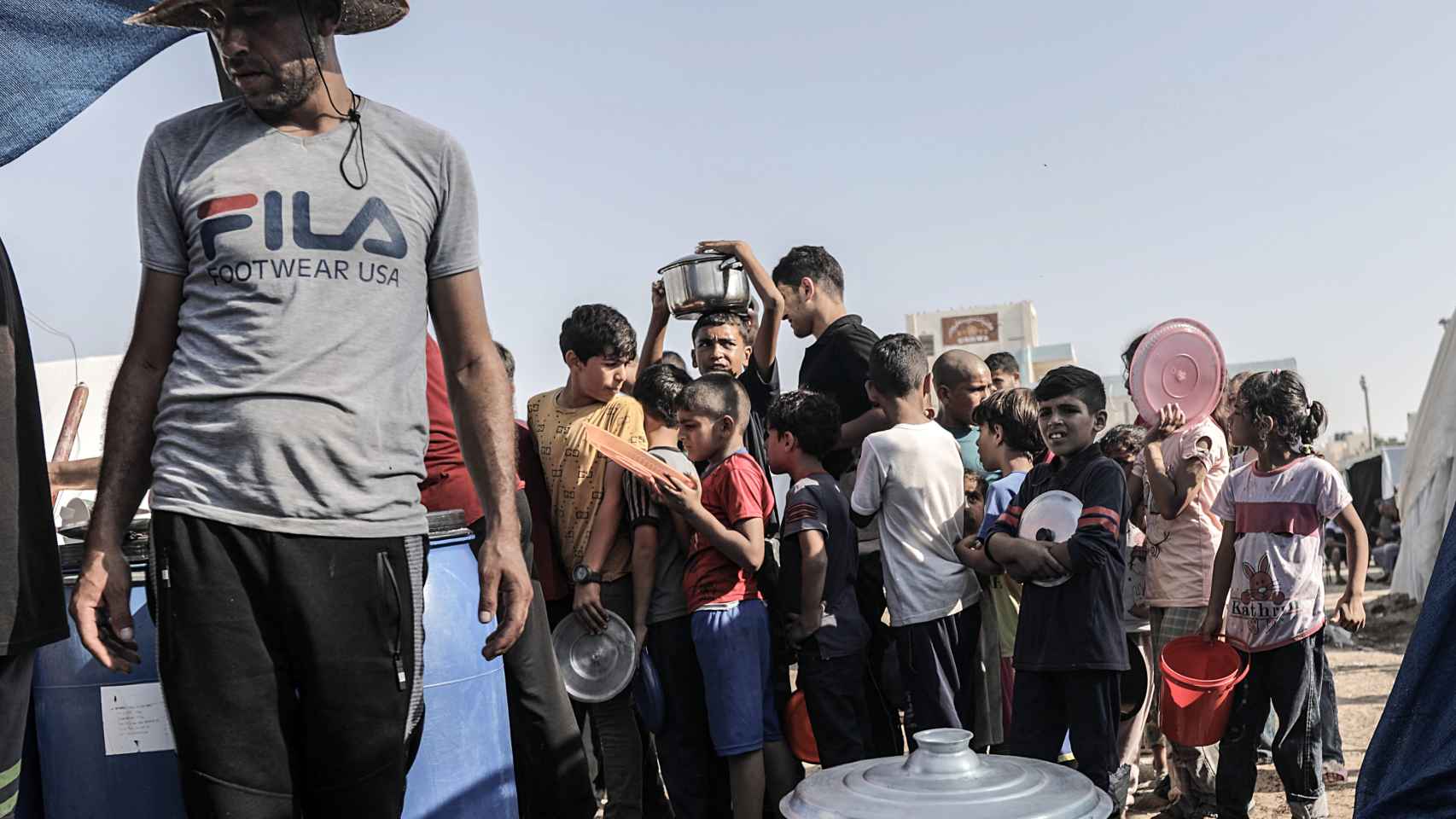 Varios niños palestinos hacen cola para recibir alimentos en el refugio de Jan Yunis, este jueves.