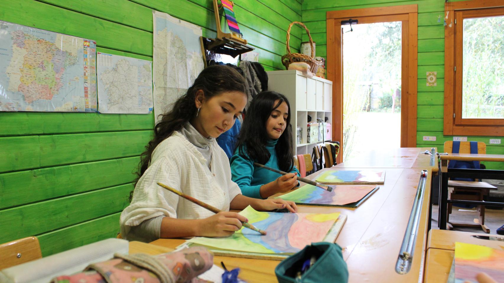 Unas niñas pintan en la escuela.