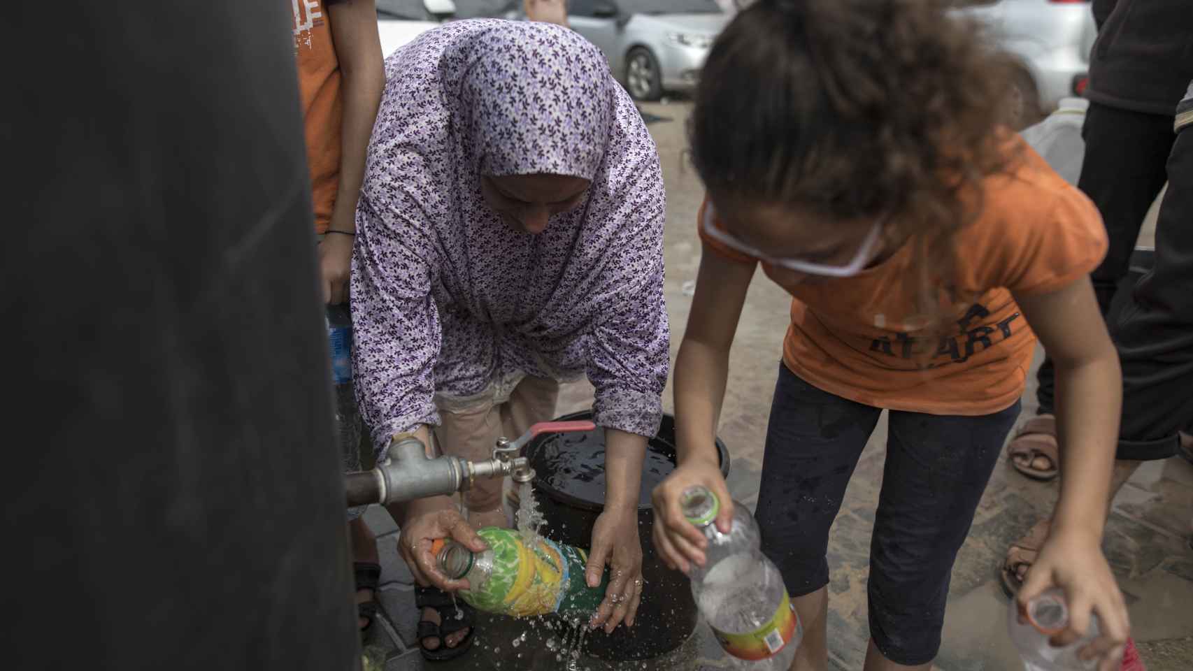 Niños gazatíes  llenan botellas con agua  en un campamento de refugiados del Programa de las Naciones Unidas para el Desarrollo (PNUD) en Khan Yunis.
