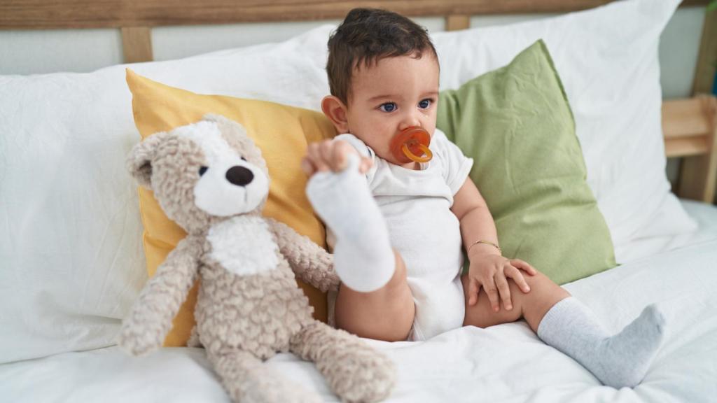 Imagen de un niño pequeño junto a su peluche en el sofá.