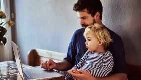 Imagen de un hombre con un niño pequeño en sus piernas mirando el ordenador.