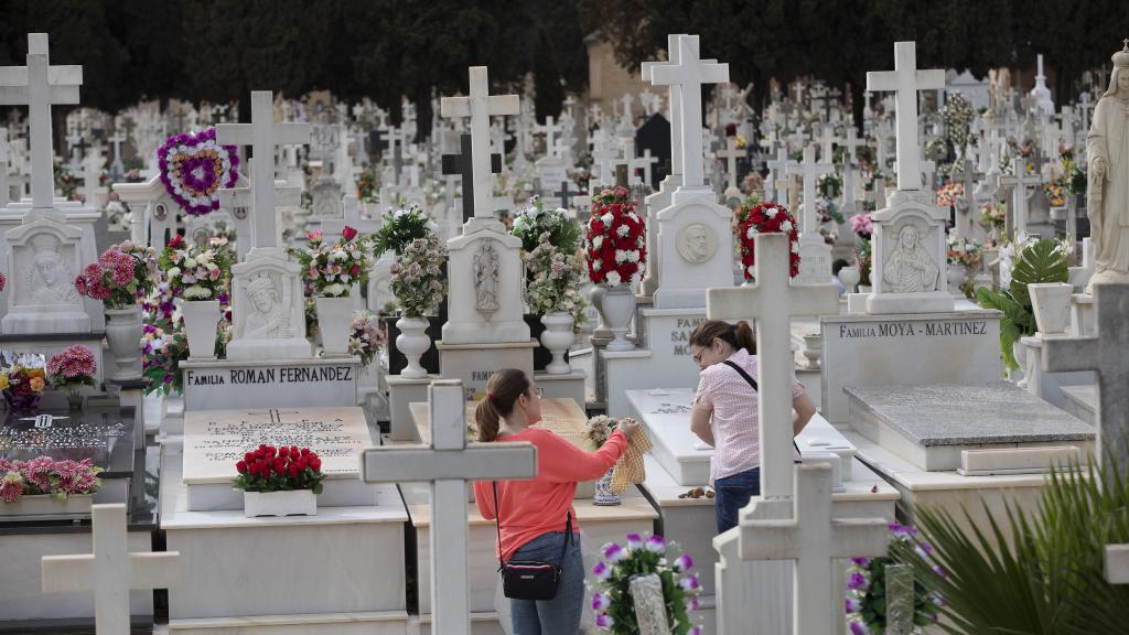 Dos mujeres en un cementerio en un 1 de noviembre, festividad de Todos los Santos.