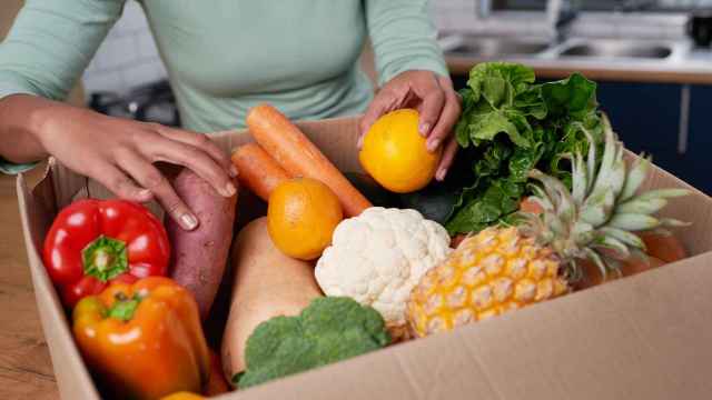 Imagen de una mujer revisando su caja de entrega de frutas y verduras.