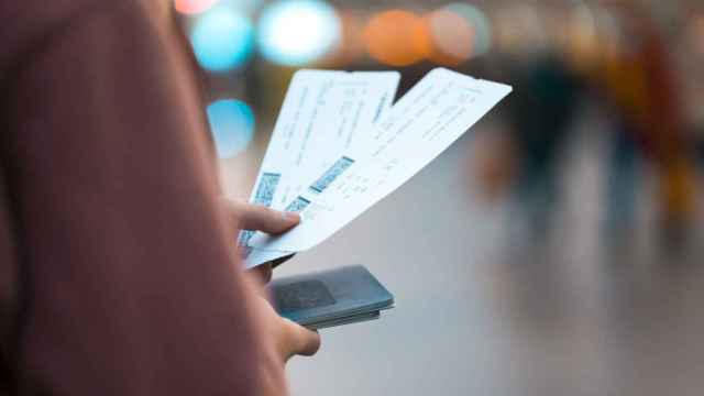 Imagen de una mujer sujetando unos billetes de avión en el aeropuerto.