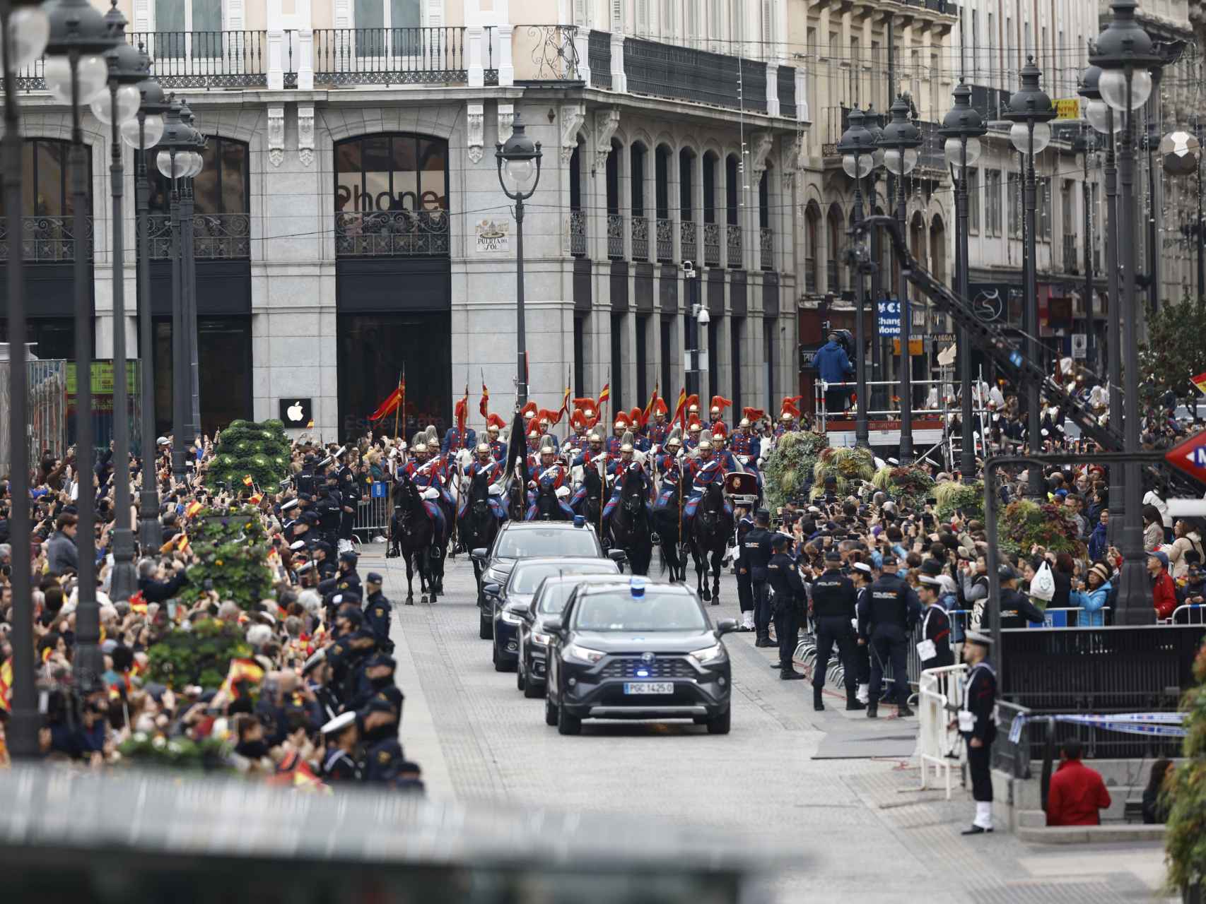 La comitiva real escoltada por la Guardia Real a su paso por la madrileña Puerta del Sol en su trayecto hacia el Palacio Real.