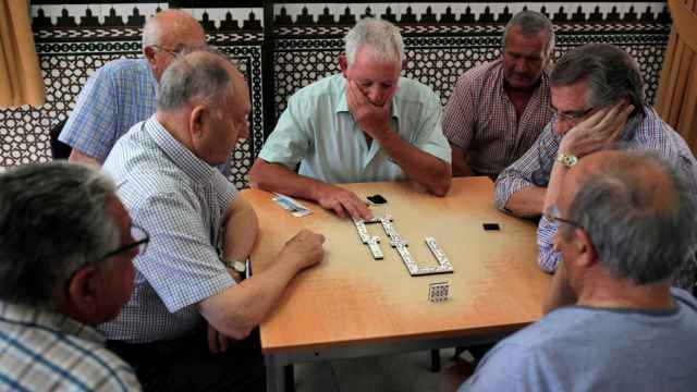 Un grupo de jubilados juega al dominó.