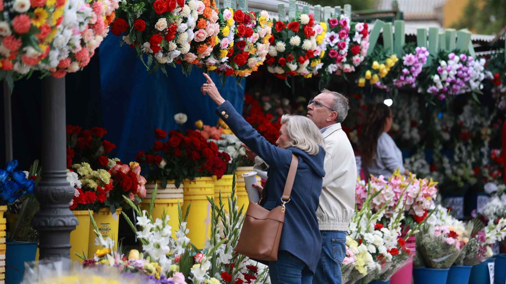Dos personas eligen flores ante el cementerio de San Fernando, en Sevilla.