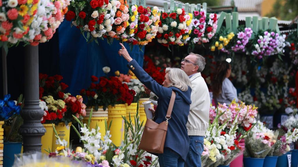 Dos personas eligen flores ante el cementerio de San Fernando, en Sevilla.