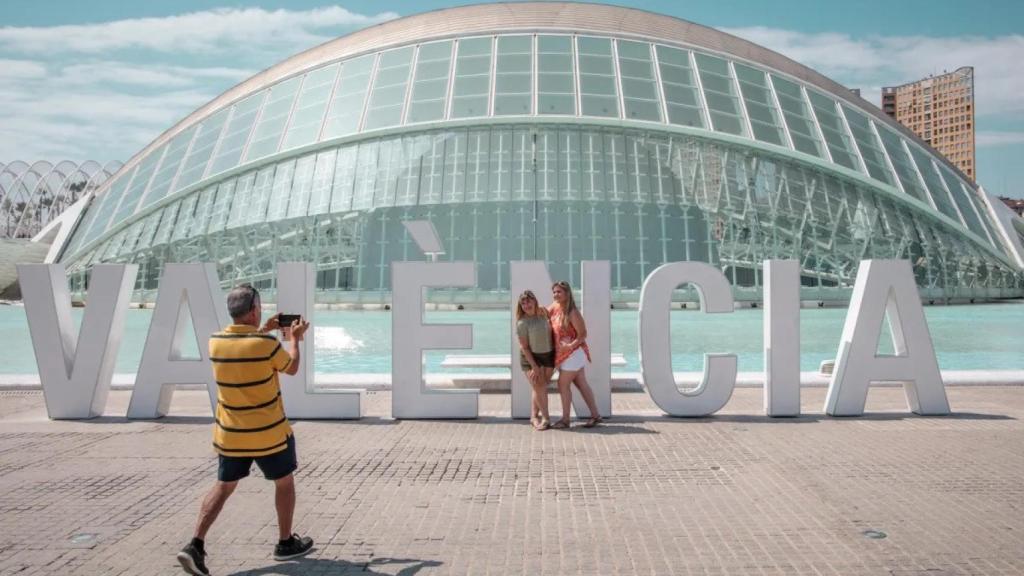 Dos personas se fotografían frente a l'Hemisfèric de la Ciudad de las Artes y las Ciencias de Valencia. Efe/Biel Aliño