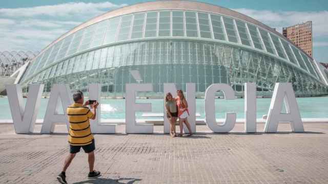 Dos personas se fotografían frente a l'Hemisfèric de la Ciudad de las Artes y las Ciencias de Valencia. Efe/Biel Aliño