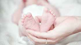 Las manos de una madre sostienen los pies de su bebé.