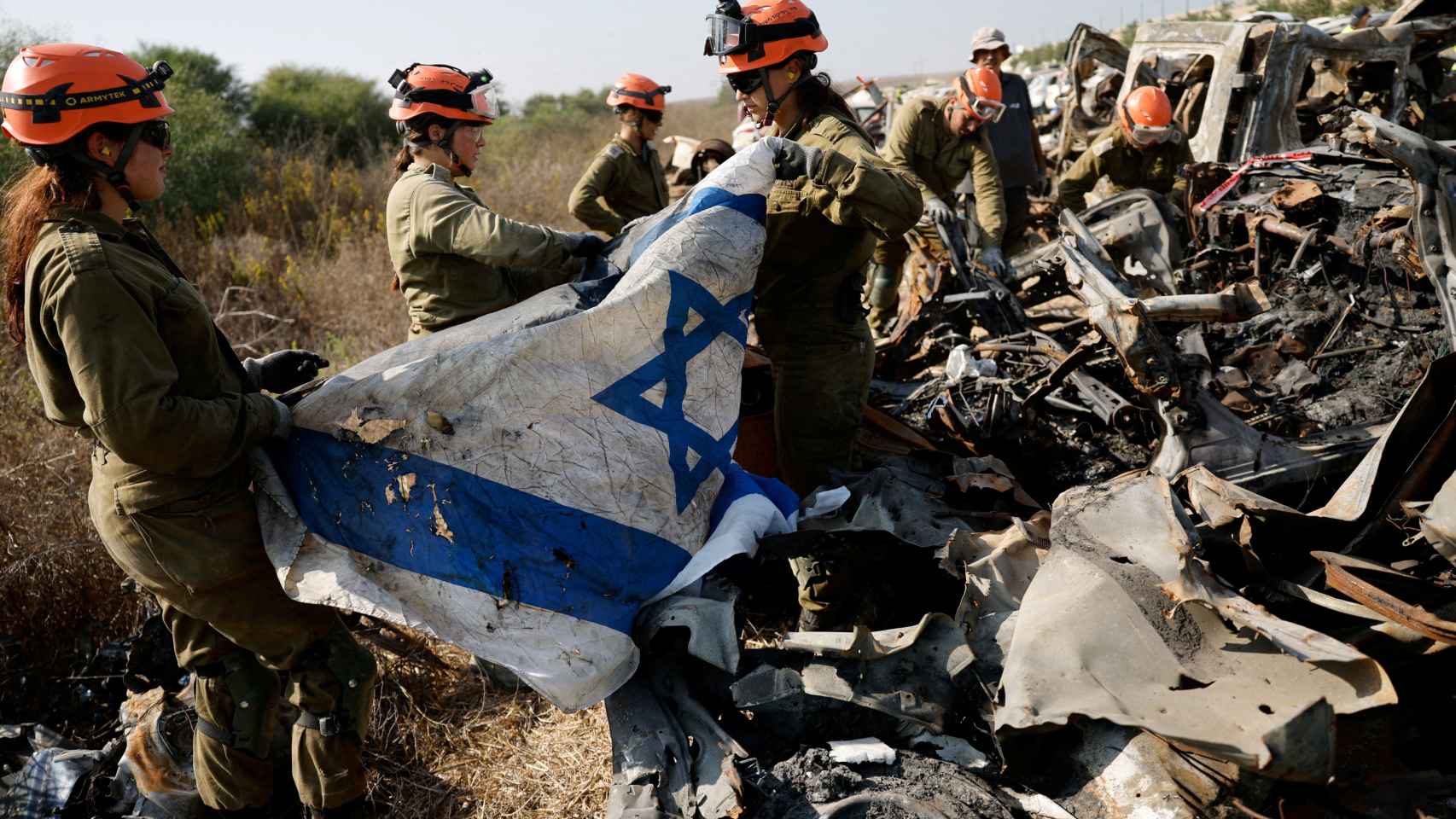 Soldados israelíes del Comando del Frente Interior recuperan una bandera israelí mientras buscan restos humanos y otras pruebas en automóviles dañados, tras el mortal ataque del 7 de octubre por parte de hombres armados de Hamas desde la Franja de Gaza, en un campo cerca de Netivot en el sur de Israel, el 1 de noviembre de 2023.