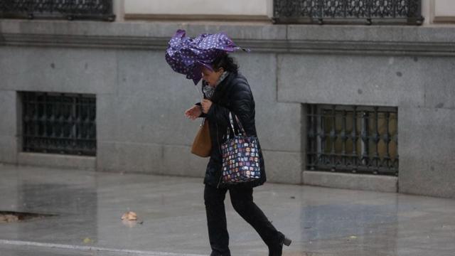 Una mujer intenta avanzar con dificultad por las fuertes rachas de viento.