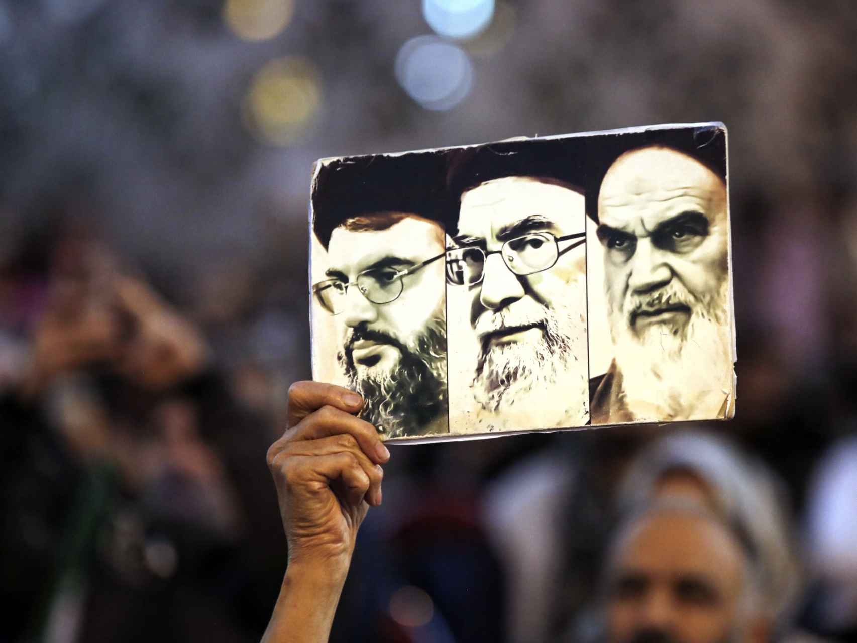 Un palestino sostiene en Teherán (Irán) los retratos de Ruhollah Khomeini, Ali Khamenei y Hassan Nasrallah.