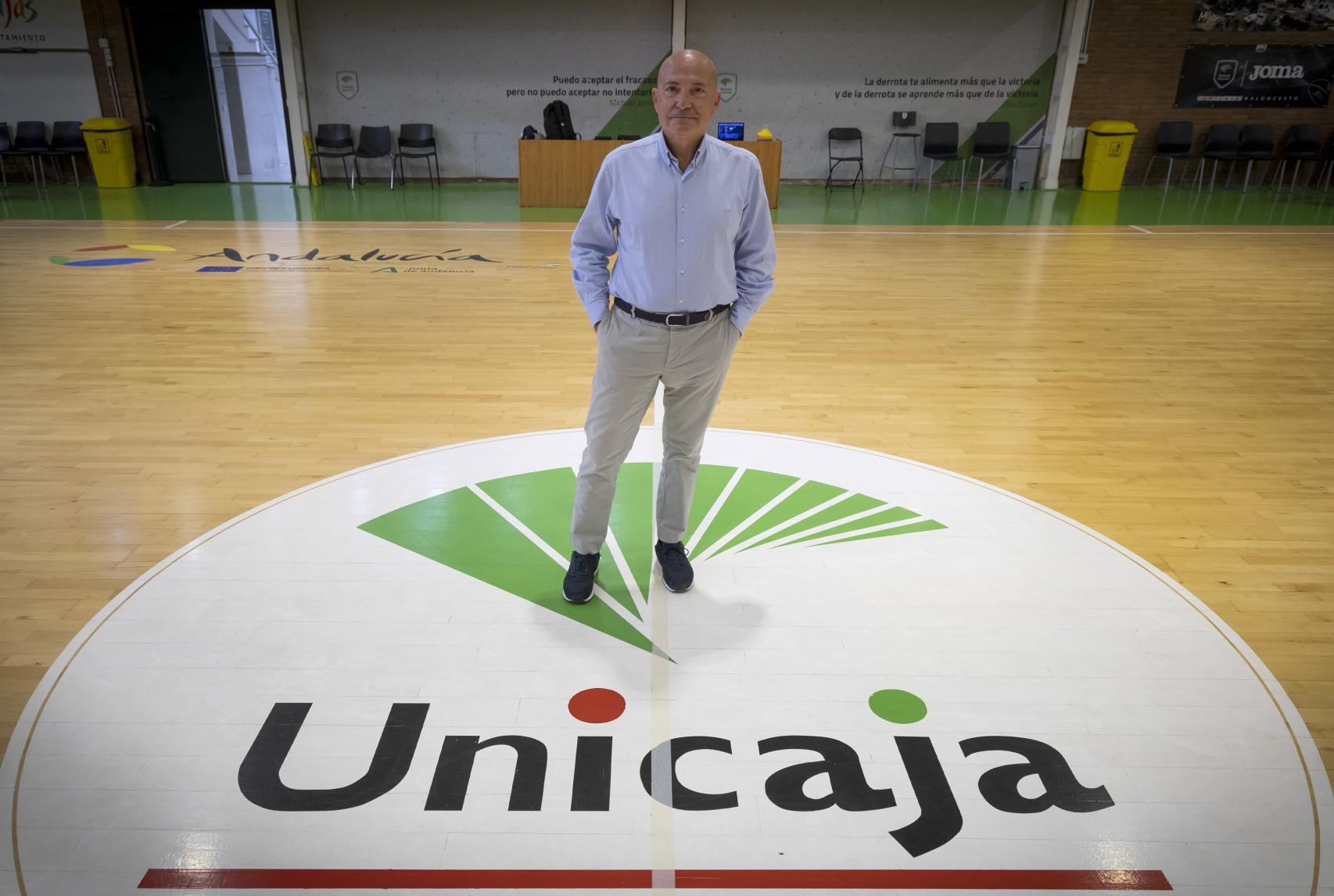 López Nieto posa junto al logo de Unicaja en la cancha de baloncesto.