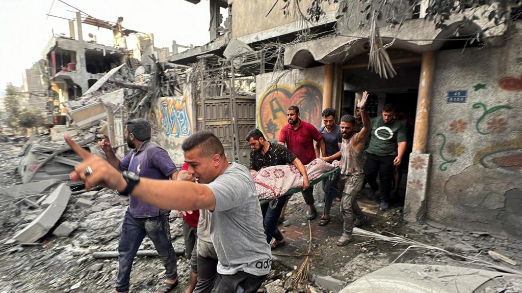 Palestinos sacan un cadáver de un edificio alcanzado por bombardeos israelíes.