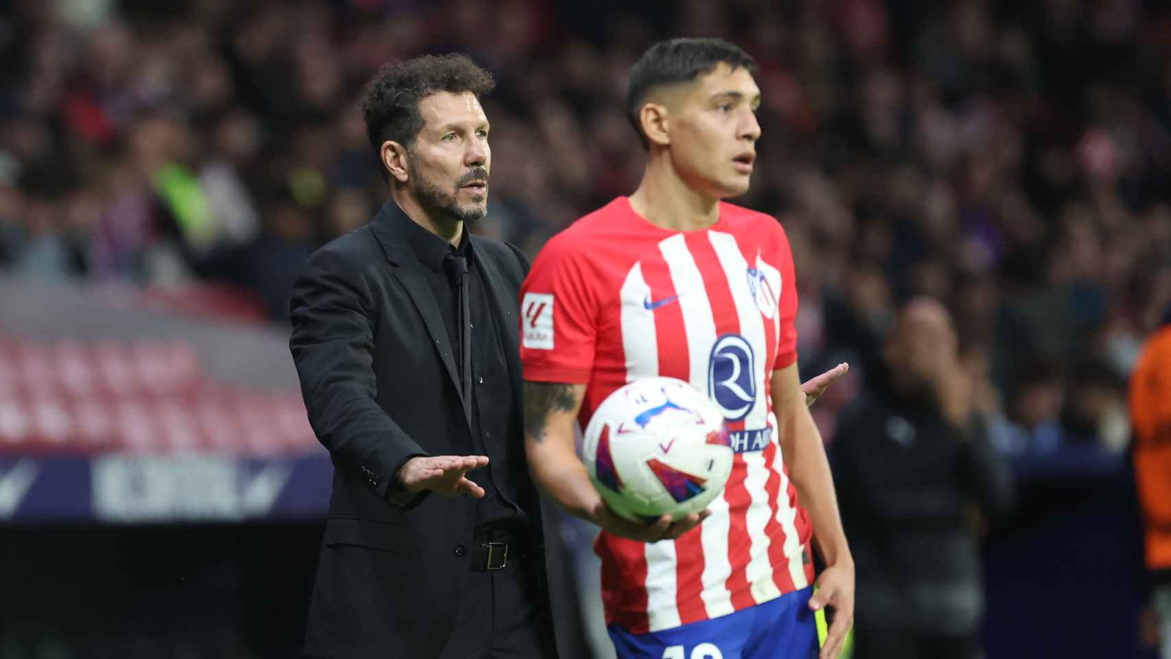Nahuel Molina va a realizar un saque de banda y Simeone da instrucciones por detrás en un partido del Atlético de Madrid.